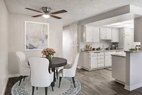 Azusa apartment for rent - A kitchen with a table and chairs in the foreground and a countertop with a sink and a plant on it in the background.