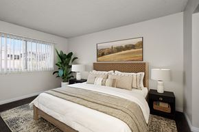Pomona apartment for rent - A bedroom with a large bed and a painting on the wall.