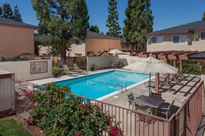 Pomona apartment for rent - A pool surrounded by a fence and patio furniture.