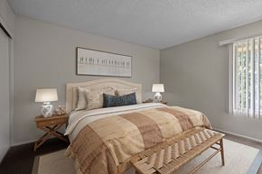 Pomona apartment for rent - A bedroom with a bed, nightstands, and a bench.