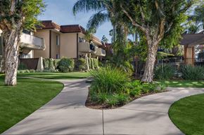 Riverside apartment for rent - A concrete walkway leads through a landscaped area in front of apartment buildings.