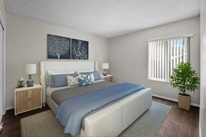 Oxnard apartment for rent - A bedroom with a bed, nightstands, and a plant.