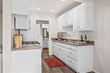 Riverside apartment for rent - A kitchen with white cabinets and a red rug on the floor.