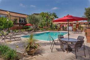 Huntington Beach apartment for rent - A poolside patio with a table and chairs.