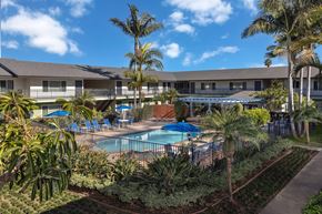 Huntington Beach apartment for rent - A pool surrounded by palm trees and plants.