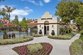 Redlands apartment for rent - A rental office is surrounded by flowers and a pool.