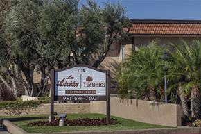 Riverside apartment for rent - A sign for Timbers Apartment Homes in front of some palm trees.