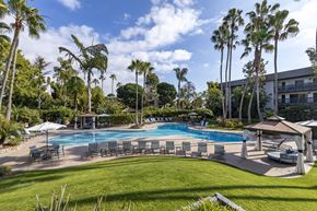 Huntington Beach apartment for rent - A large swimming pool surrounded by palm trees and lounge chairs.