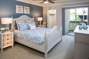 Huntington Beach apartment for rent - A bedroom with a large bed, a dresser, and a ceiling fan.