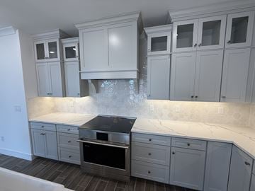 Chandler house for rent - A kitchen with white cabinets and a black stove top.