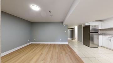 Toronto apartment for rent - A kitchen with a refrigerator, stove, and oven is visible from the living room.