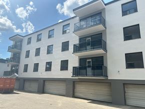 Toronto apartment for rent - A white apartment building with black railings and closed grey garage doors.