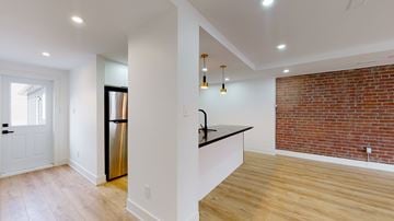 Toronto apartment for rent - A kitchen with a refrigerator, sink, and a counter with a brick wall in the background.