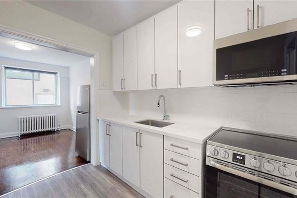 Toronto apartment for rent - A kitchen with white cabinets and a black microwave.