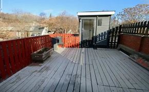 Toronto apartment for rent - A wooden deck with a small building and a black fence.