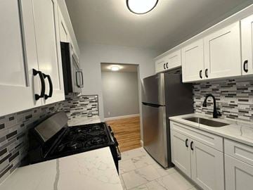 Hightstown apartment for rent - A kitchen with white cabinets and a black stove top.