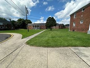 Hightstown apartment for rent - A grassy area in front of a brick building with a tree in the middle.