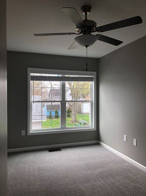 Kokomo triplex for rent - a living room with a large window and a ceiling fan