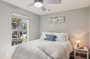 Spartanburg apartment for rent - A bedroom with a bed, a ceiling fan, and a window with a view of a parking lot.