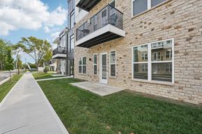 Fortville apartment for rent - A brick building with a balcony and a walkway in front.
