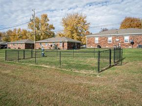 Franklin apartment for rent - A person is standing in a grassy field next to a fence at Stonebrook of Franklin Apartments, Franklin, Indiana