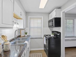 Kettering apartment for rent - A kitchen with a black stove top oven and white cabinets at Huntley Ridge Apartments, Kettering, Ohio