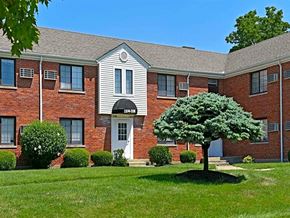 Kettering apartment for rent - A tree in front of a building with a white door and windows at Huntley Ridge Apartments, Kettering, OH, 45419