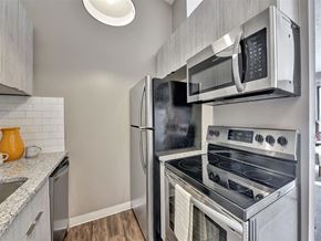 Milford apartment for rent - A modern kitchen with a stainless steel refrigerator, oven, and microwave at The Reserve at Grand Valley Apartments, Milford, OH