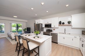Roseville apartment for rent - A modern kitchen with white cabinets and a dining table.