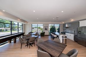 Roseville apartment for rent - A modern community room kitchen with a dining table, comfortable chairs and shuffle board game.