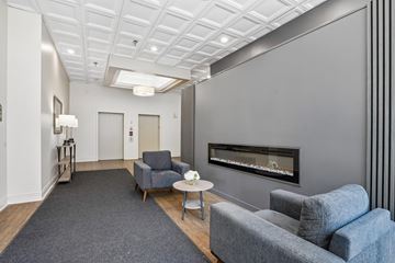 St. Paul apartment for rent - A living room with a grey couch, a grey chair, a grey rug and a fireplace.