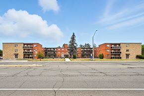 Hamilton apartment for rent - A large building with a parking lot in front of it.