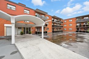 Hamilton apartment for rent - A red brick building with a white overhang and a puddle of water in front.