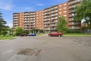 Stoney Creek apartment for rent - A red truck is parked in a parking lot in front of a large apartment building.