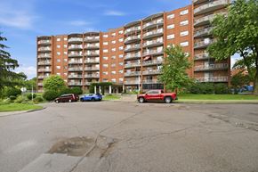 Stoney Creek apartment for rent - A red truck is parked in a parking lot in front of a large apartment building.