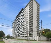Hamilton apartment for rent - A tall residential building with a grey facade and balconies on each floor.