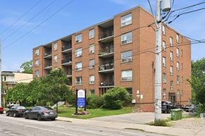 Hamilton apartment for rent - A large brick apartment building with a blue sign in front.