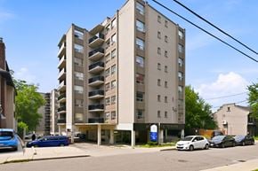 Hamilton apartment for rent - A tall apartment building with a blue car parked in front.