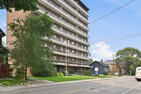 Hamilton apartment for rent - A tall apartment building with a bus parked in front of it.