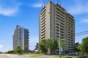 Hamilton apartment for rent - A tall building with a flat roof and a balcony on the top floor stands next to a shorter building with a curved roof.