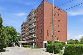 Hamilton apartment for rent - A red brick apartment building with a parking lot in front.