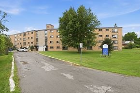 Welland apartment for rent - A street view of a residential area with apartment buildings and a blue recycling bin.