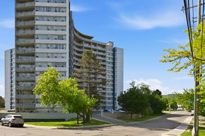 Hamilton apartment for rent - A tall building with a curved design and balconies on the upper floors.