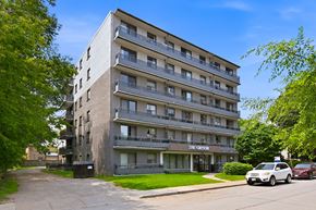 Hamilton apartment for rent - A large apartment building with a parking lot in front.