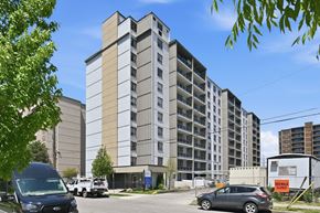 Hamilton apartment for rent - A large building with a parking lot in front of it.