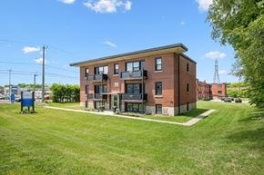 Kitchener apartment for rent - A red brick building with a green lawn in front.