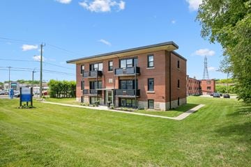 Kitchener apartment for rent - A red brick building with a green lawn in front.