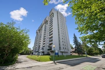 Kitchener apartment for rent - A tall white building with a green lawn in front.
