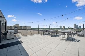 Kitchener apartment for rent - A rooftop patio with a table and chairs overlooking a city skyline.