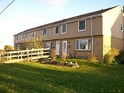 Cobourg apartment for rent - A house with a brown and beige exterior has a white door and a small porch.